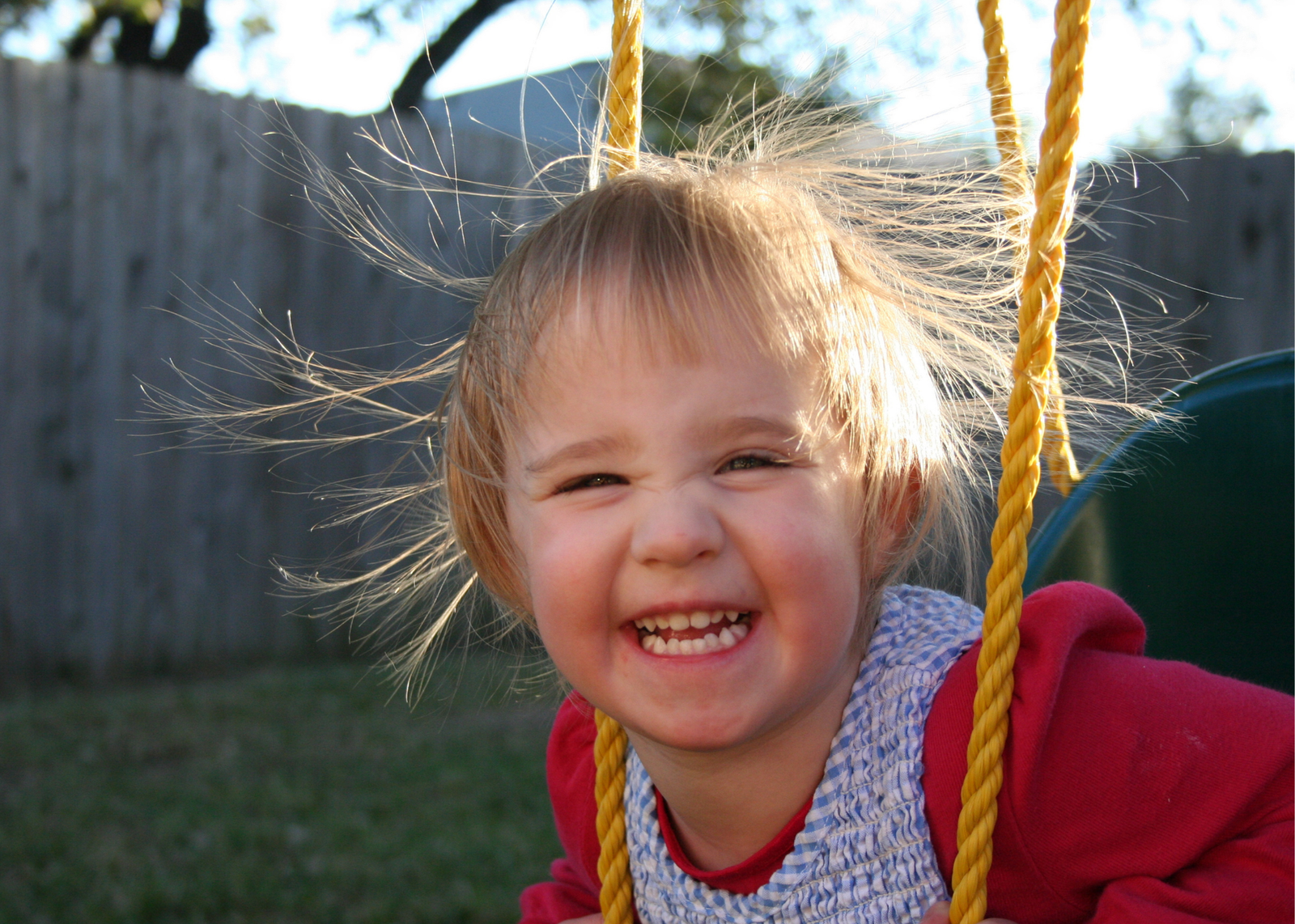 a smiling child on a swing with static hair