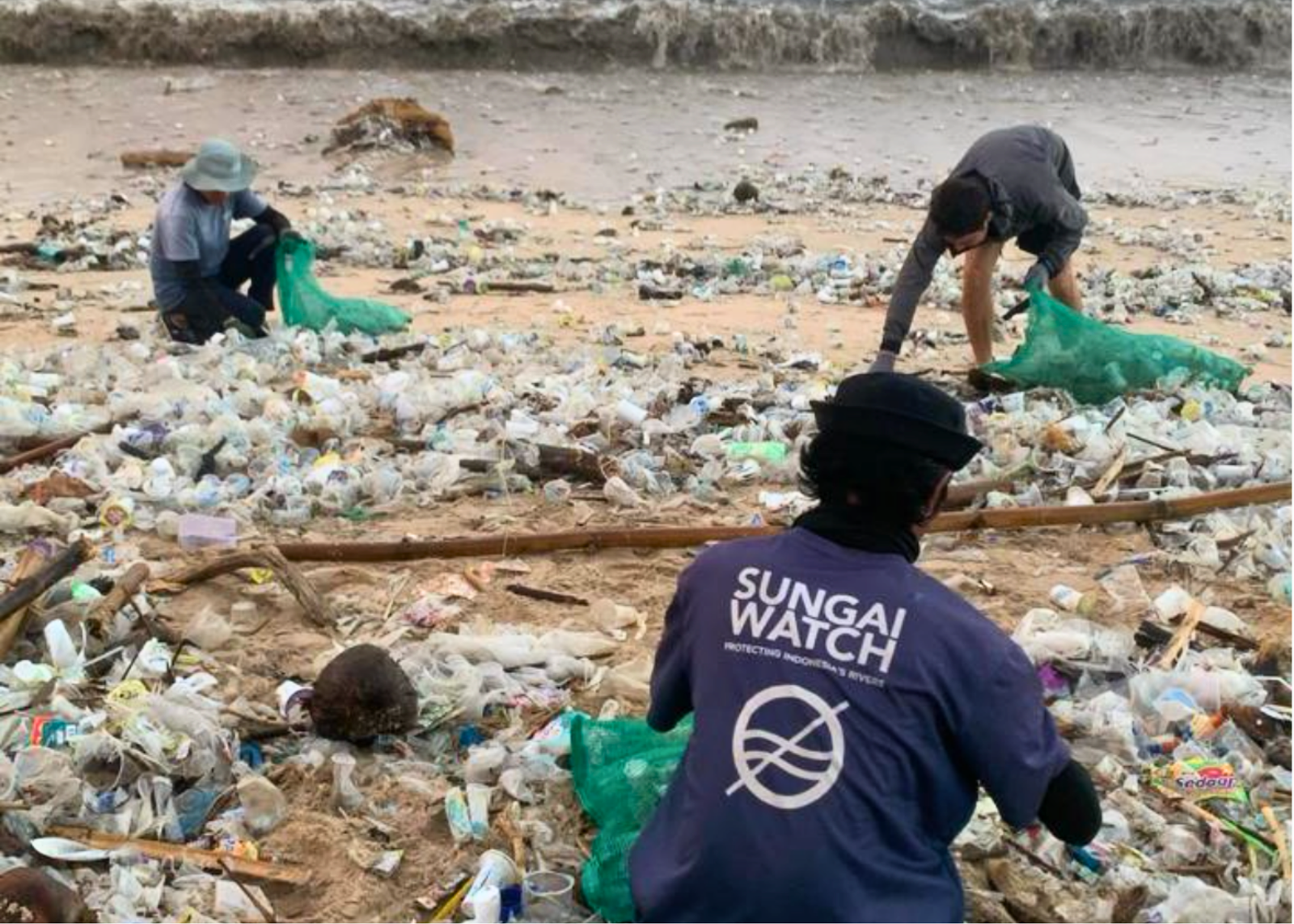 3 Sungai Watch Volunteers collect plastic waste from a heavily polluted beach