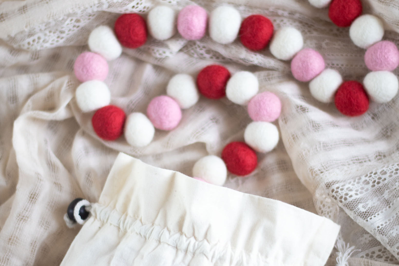 a white, pink, and red garland on a white lace fabric