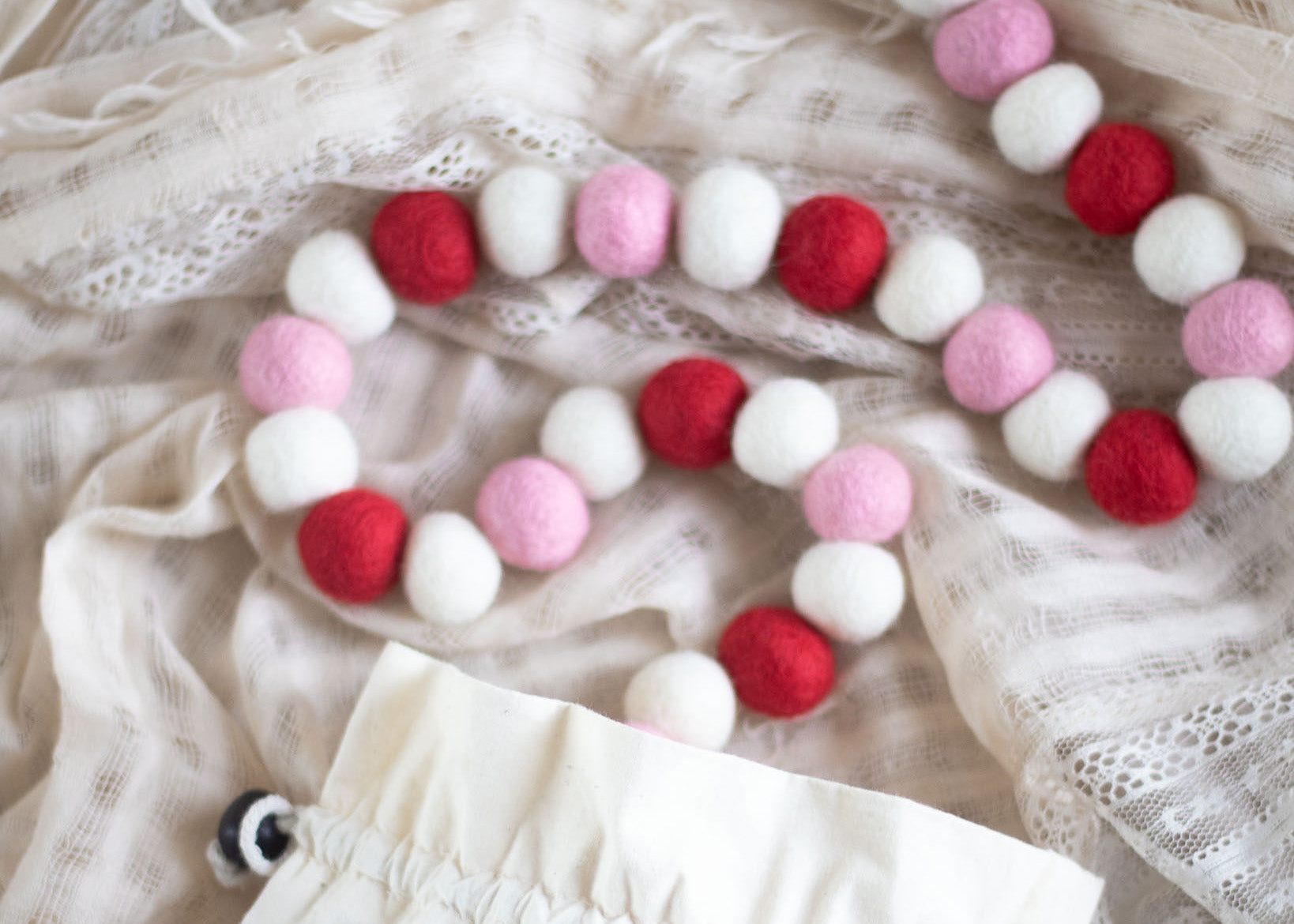 white, pink, and red garland on a white lace fabric